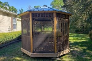 Oblong wooden outdoor seating gazebo with screening, perfect for enjoying nature in comfort.