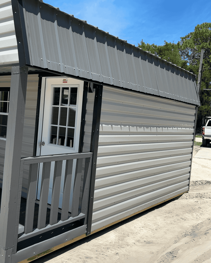 Side view of 10x16 Ash Gray Gambrel Cabin showing Black trim, Charcoal metal roof, 4' porch with rails, and colonial windows