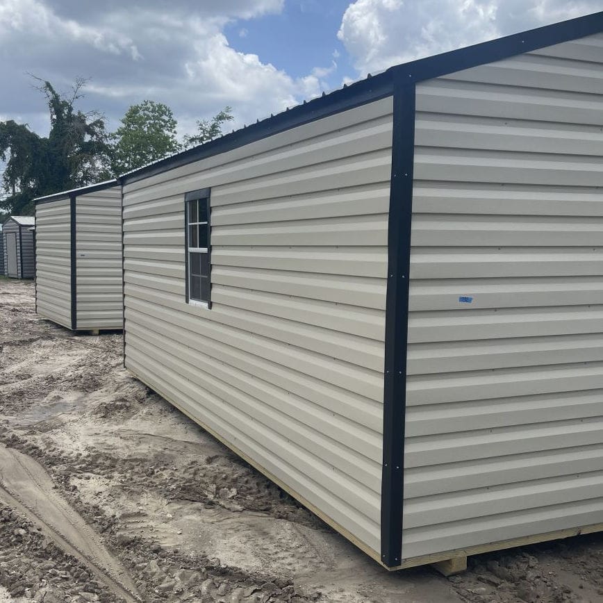 Side view of 10x20 Light Stone Steel Americana Shed showing Black trim, Galvalume metal roof, colonial windows, and gable vents