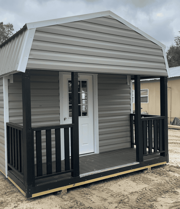 Front view of 12x20 Clay Steel Gambrel Cabin with 4' porch and white rails, 9-lite inswing door, and two colonial windows