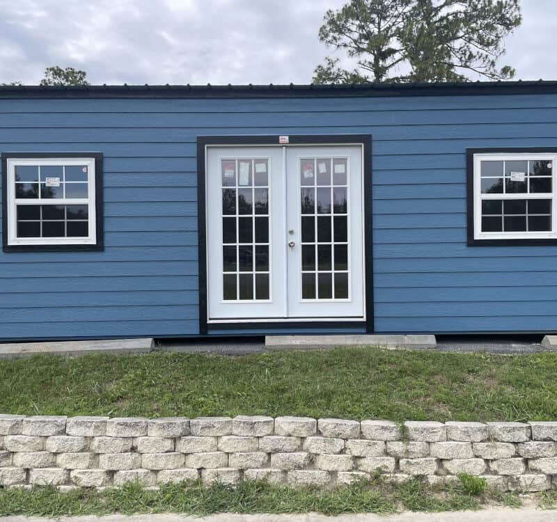 Front view of 12x24 Hawaiian Blue Vista Shed with Black trim and Galvalume roof, featuring elegant 15-light French doors and multiple windows