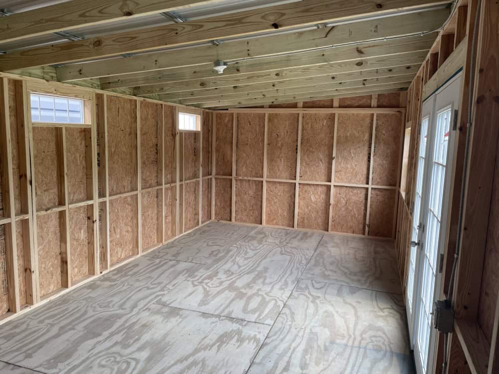 Spacious interior of 12x24 Vista Shed with wood stud framing, pressure treated plywood floor, and bright natural light from French doors and windows