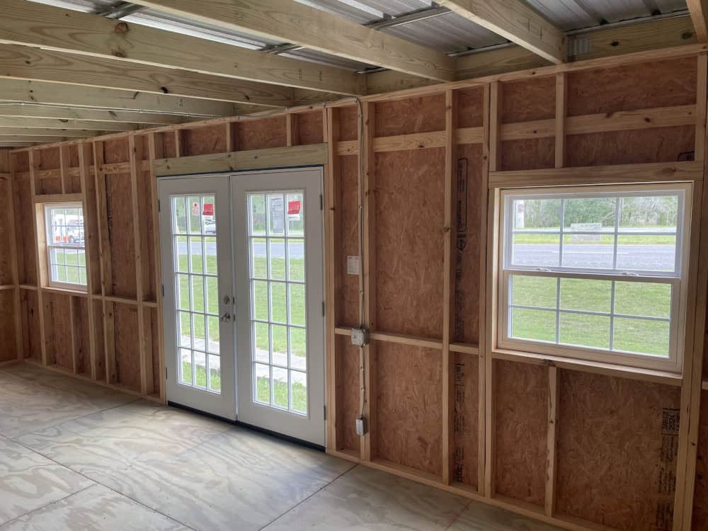 Interior view of 12x24 Hawaiian Blue Vista Shed showing wood stud walls, high ceilings, and pre-wired electrical package