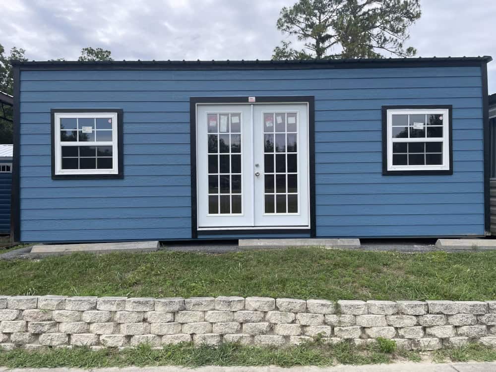 Front view of 12x24 Hawaiian Blue Vista Shed with Black trim and Galvalume roof, featuring elegant 15-light French doors and multiple windows