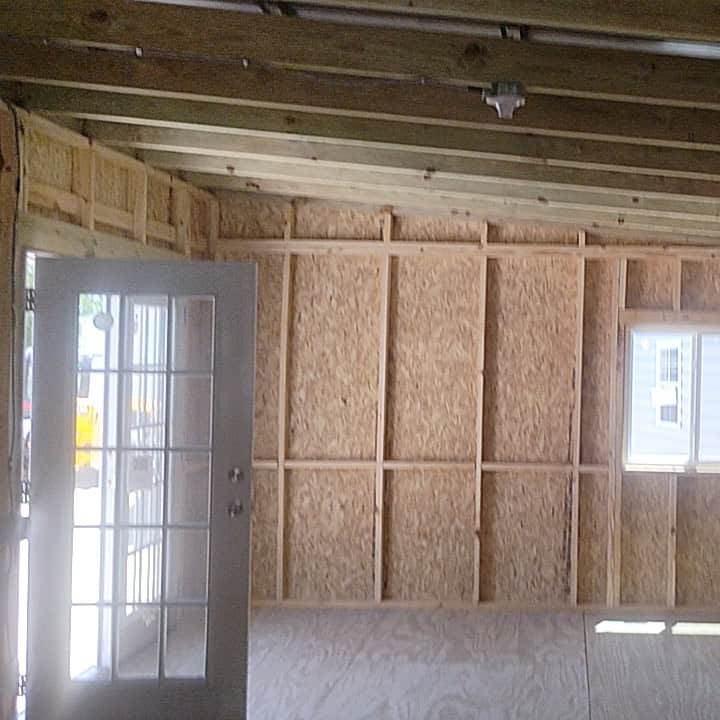 Spacious interior of 14x24 Light Stone Vista Shed with wood stud framing, pressure treated flooring, and bright natural light from French doors and windows
